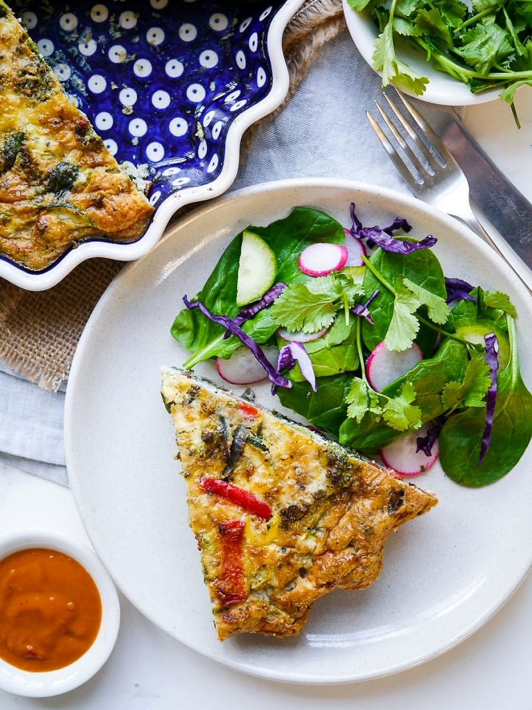 Vegetable frittata in blue pie dish with side salad