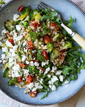 Broccoli Buckwheat Salad with chopped semi dried tomatoes topped with feta cheese in bowl - recipe by Nourish Every Day