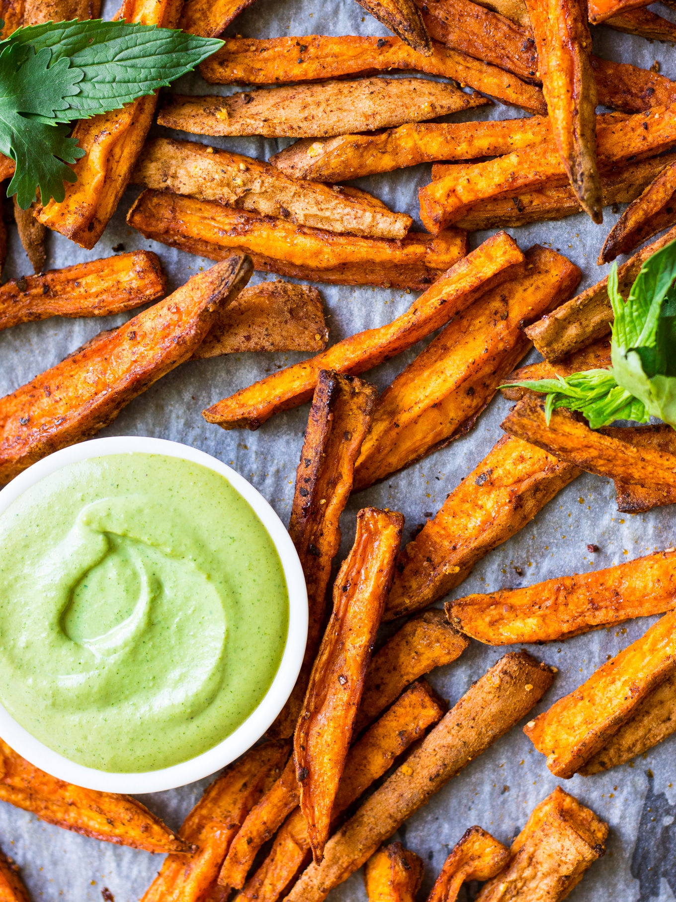 Small bowl of Cashew Tahini Herb Sauce served on a tray with sweet potato fries.