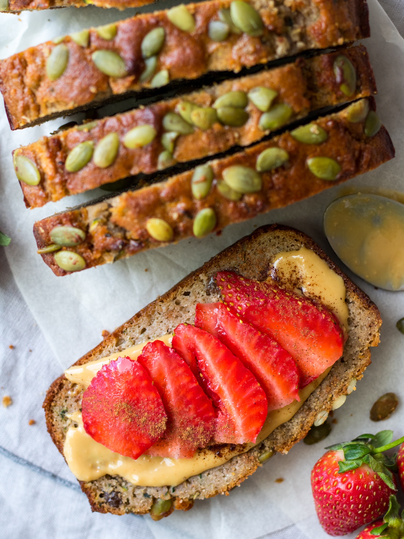 Apple Zucchini Snack Cake shot from top down, close up, one slice flat topped with nut butter and sliced strawberries
