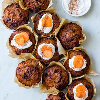 Healthy Carrot Cake Muffins, muffins clustered together on a marble surface, half iced with coconut yoghurt