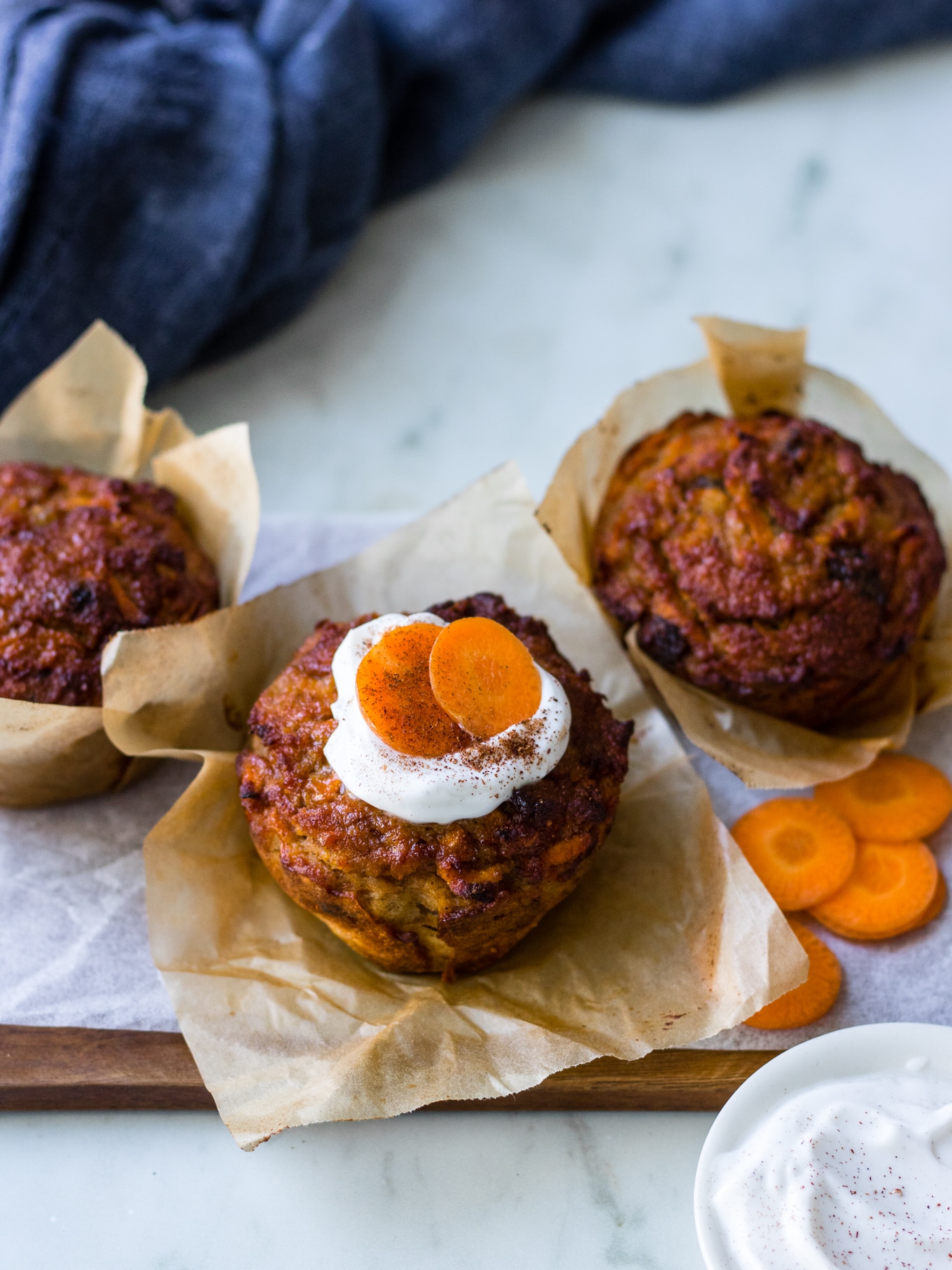 Healthy Carrot Cake Muffins, three muffins in a zig zag across wooden chopping board