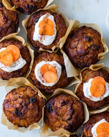 Healthy Carrot Cake Muffins, muffins clustered together on a marble surface, half iced with coconut yoghurt
