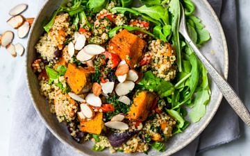 Roast pumpkin quinoa salad close up in grey shallow bowl, fork nestled in side