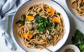vegan mushroom pasta with roast pumpkin chunks and parsley garnish, white bowl with blue rim