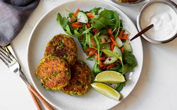 thai salmon cakes on white plate with side salad and lime