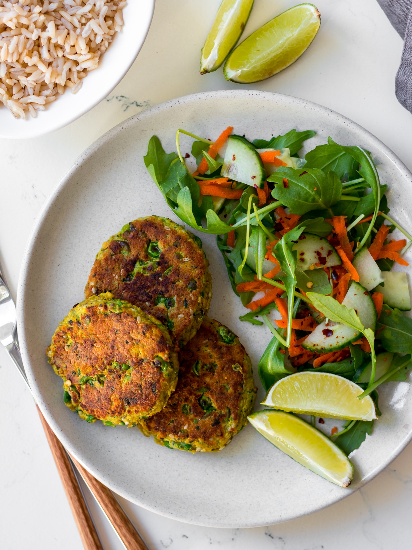 thai salmon cakes on white plate with side salad and lime