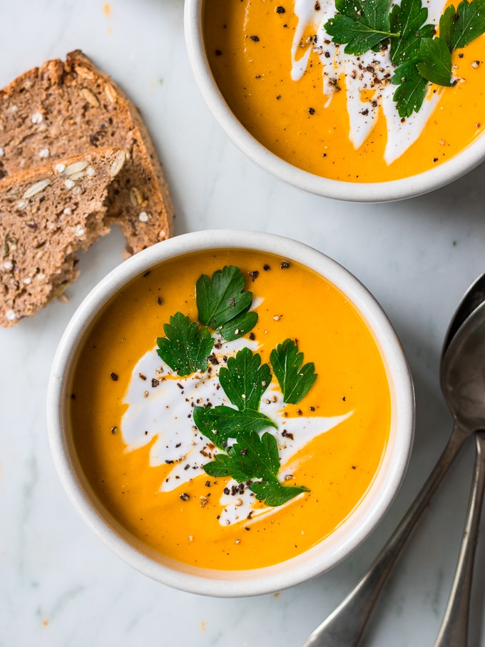 pumpkin soup bowl garnished with coconut cream and herbs