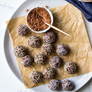 kakadu plum and ginger energy balls on white plate with cacao powder in dish