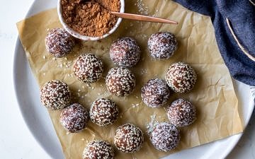 kakadu plum and ginger energy balls on white plate with cacao powder in dish