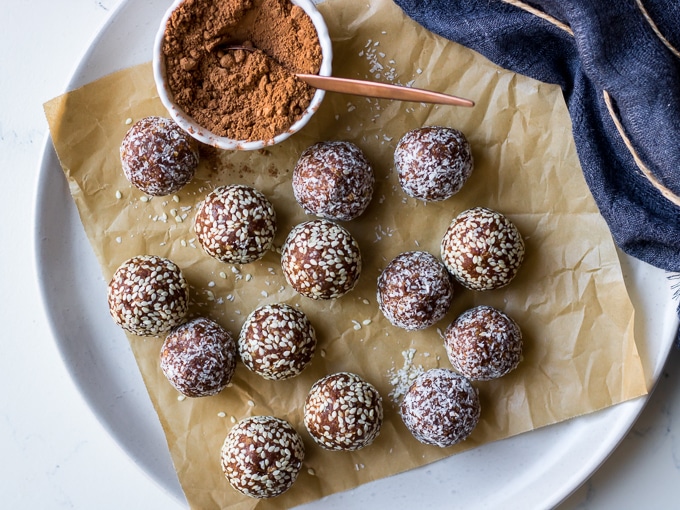 kakadu plum and ginger energy balls on white plate with cacao powder in dish