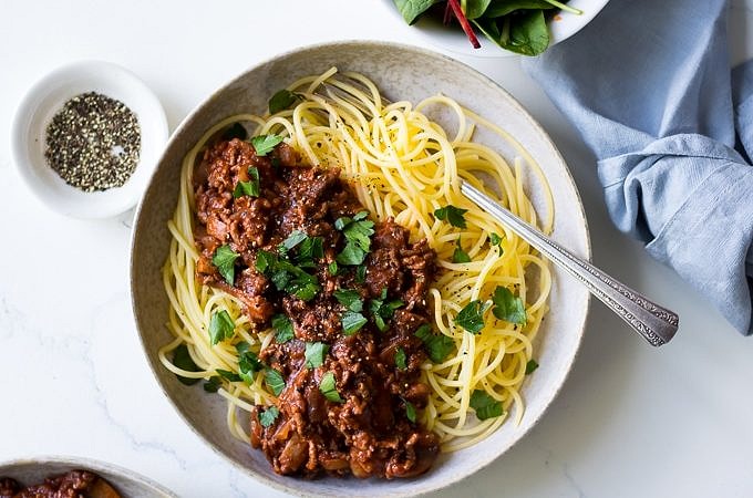 Red Wine Bolognese in ceramic bowl, spaghetti, parsley garnish