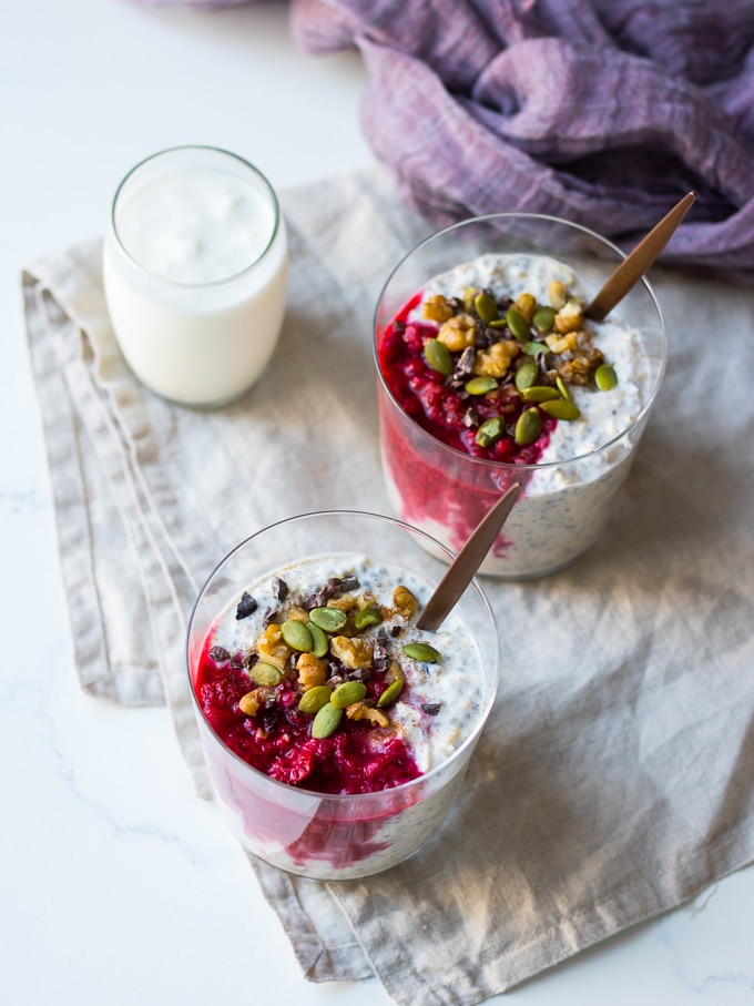 raspberry kefir overnight oats with glasses, topped with nuts, seeds, cacao nibs