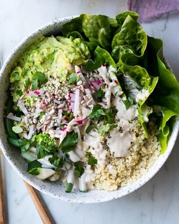 vegan protein buddha bowls with green vegetables, avocado smash, quinoa in white speckled bowls