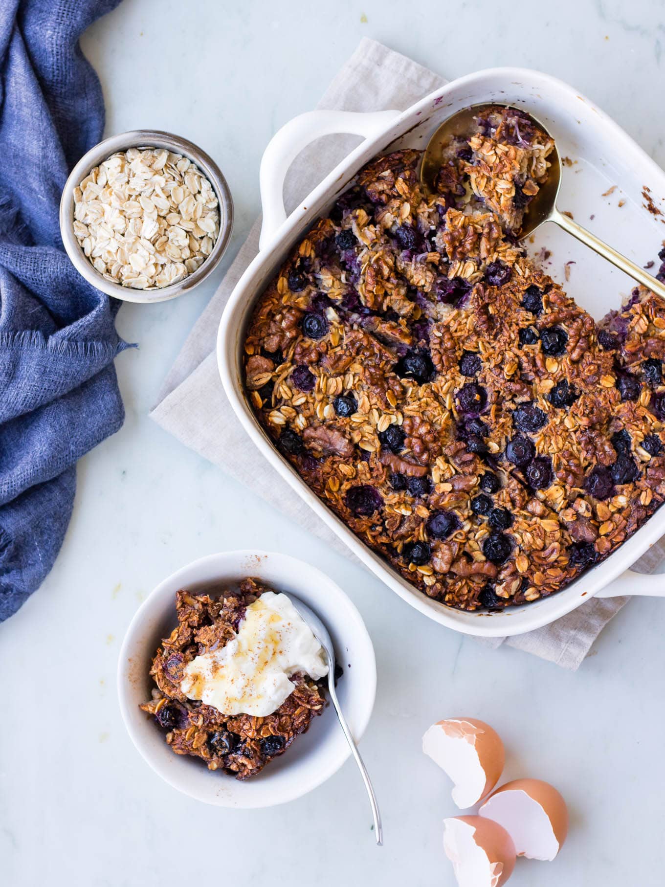 coconut blueberry baked oats in white baking dish, plus serving bowl