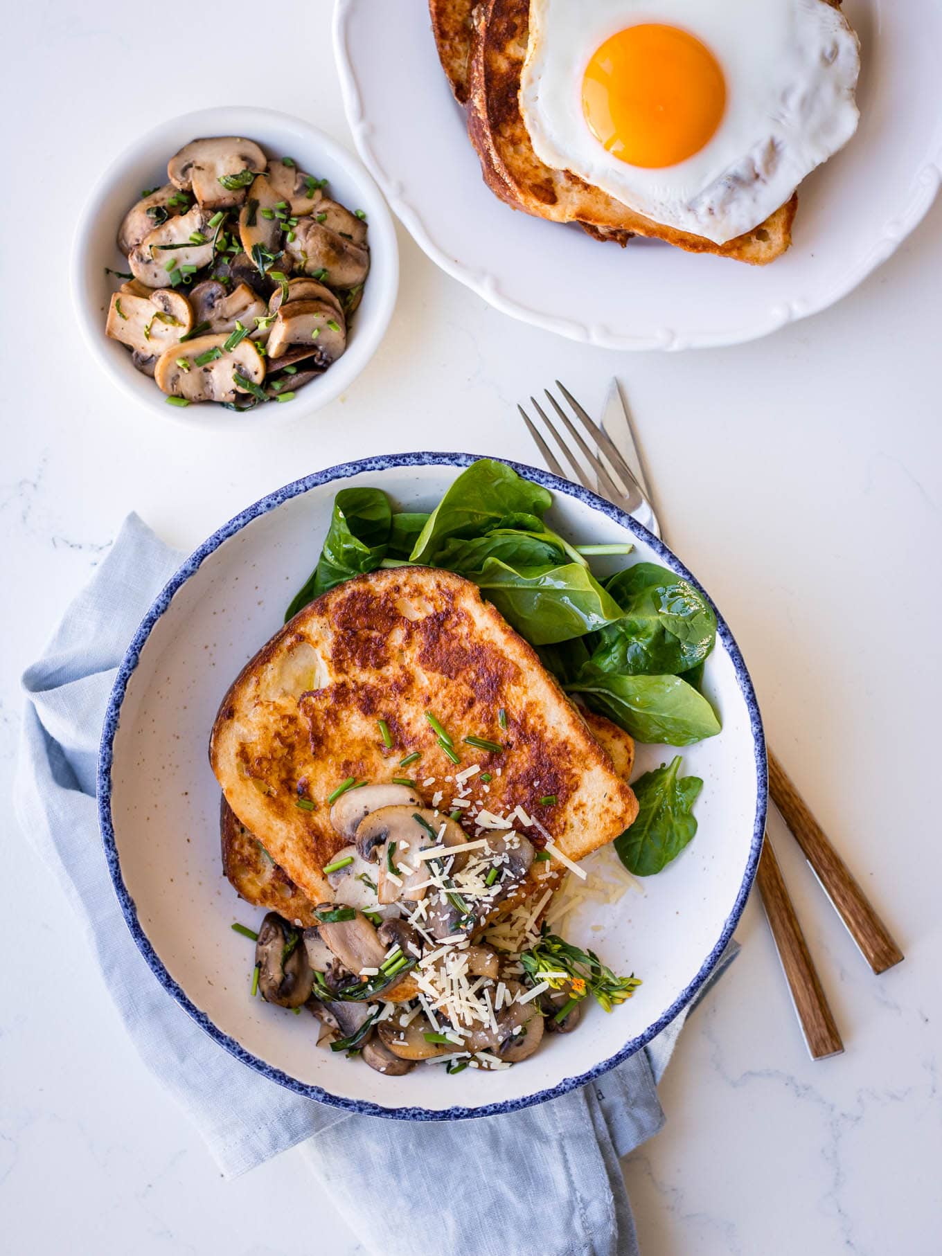 Savoury french toast with mushrooms and parmesan, white bowl, blue napkin
