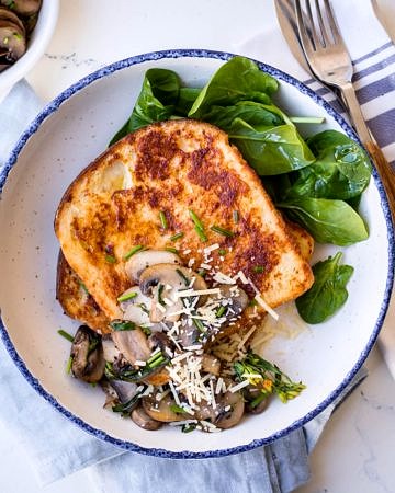 Savoury french toast with mushrooms and grated parmesan, white bowl