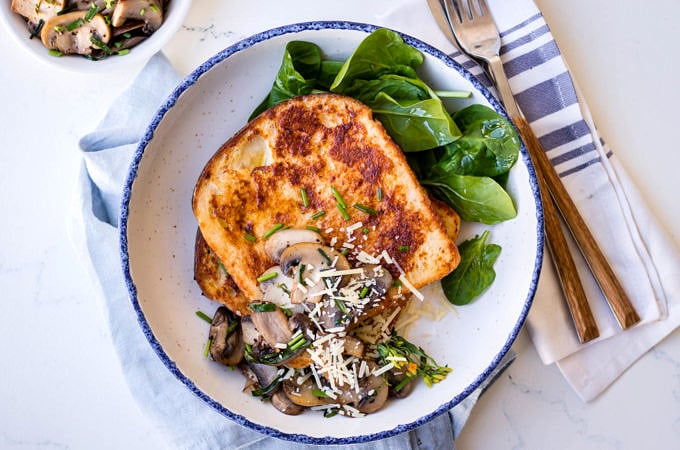 Savoury french toast with mushrooms and grated parmesan, white bowl