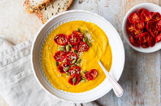 Cauliflower, sweet potato and red lentil soup in white patterned bowl with bread