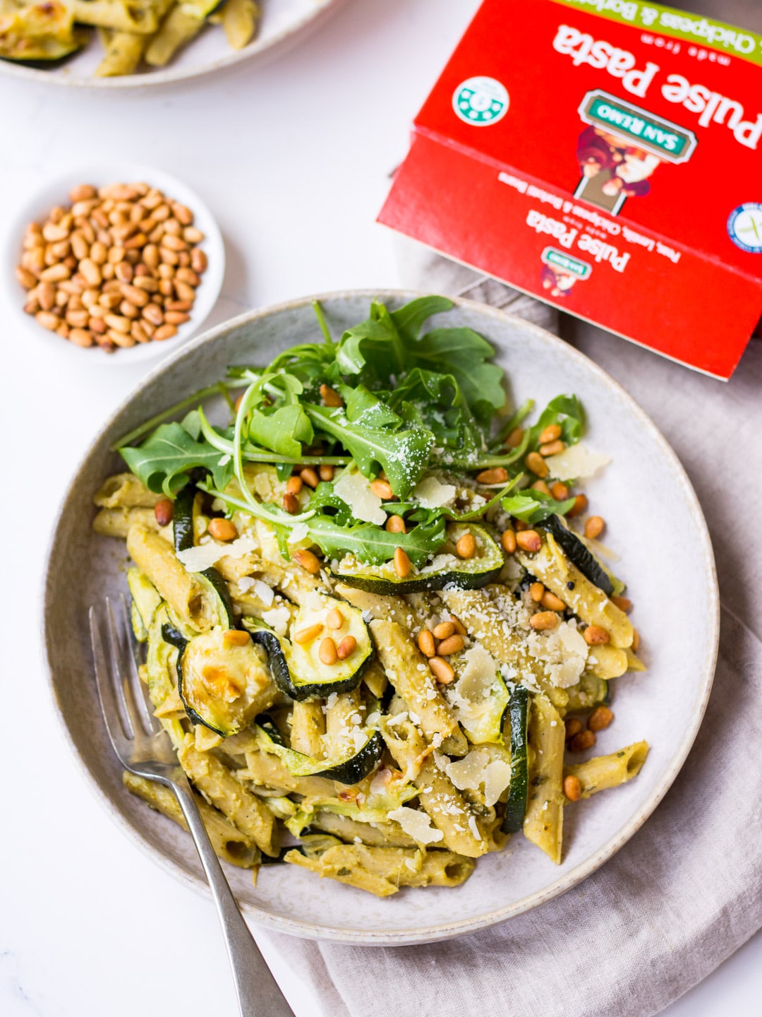 Pesto Pulse Pasta with Roasted Zucchini served in a grey ceramic bowl, with pine nuts