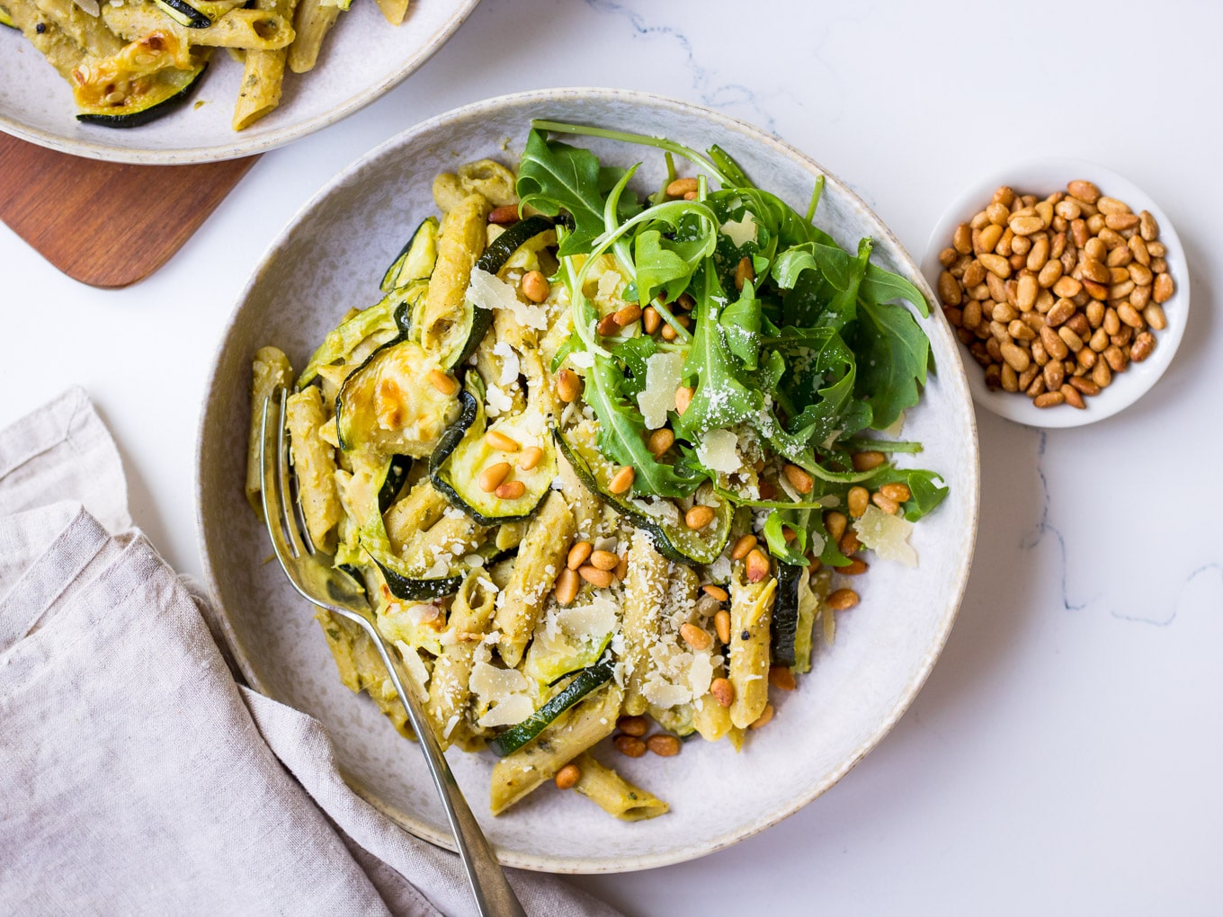 Pesto Pulse Pasta with Roasted Zucchini served in a grey ceramic bowl, with pine nuts