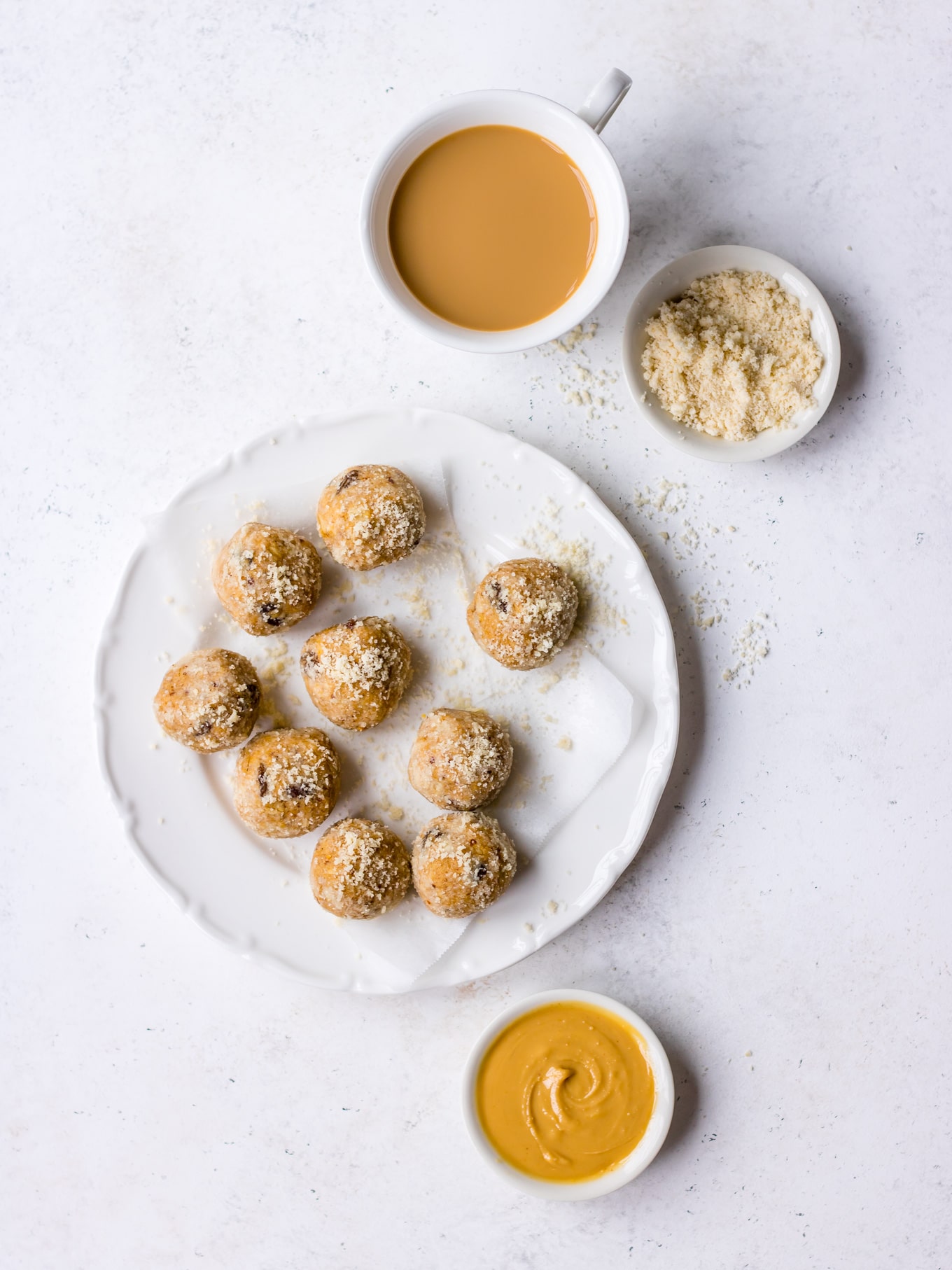 No bake Lactation Bites arranged on a white plate, scattered with almond meal (by Nourish Every Day)