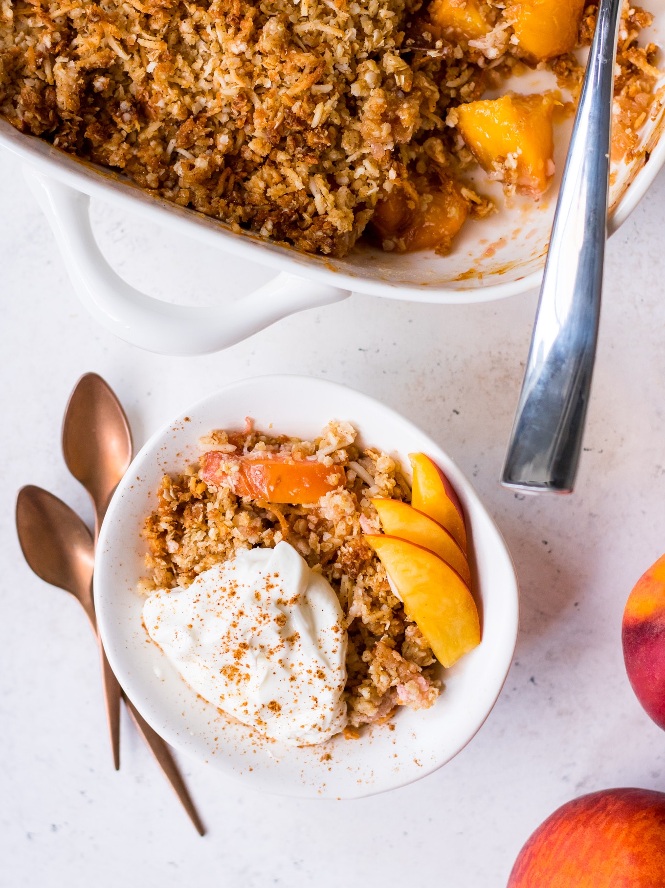 Close up of gluten free stone fruit crumble topped with yoghurt, cinnamon and nectarine slices