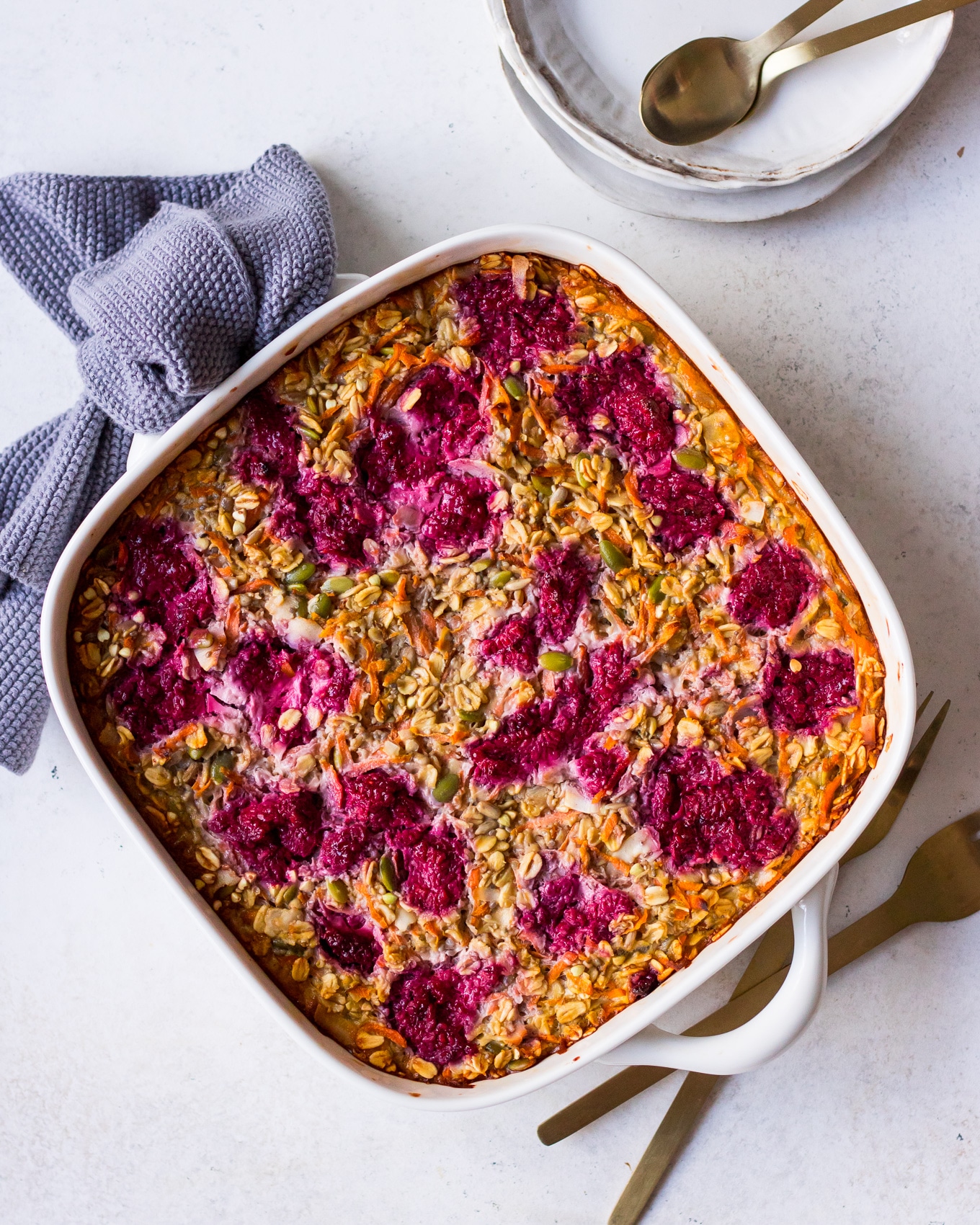 Carrot baked oatmeal with raspberries in white baking dish