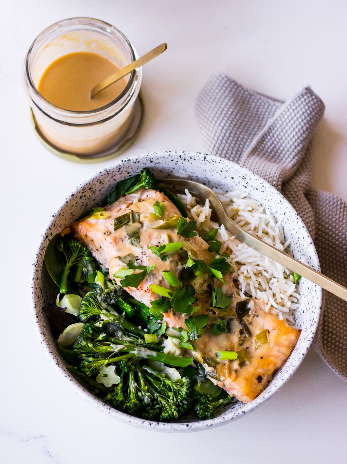 Tahini Miso Salmon in speckled white bowl with sauce jar