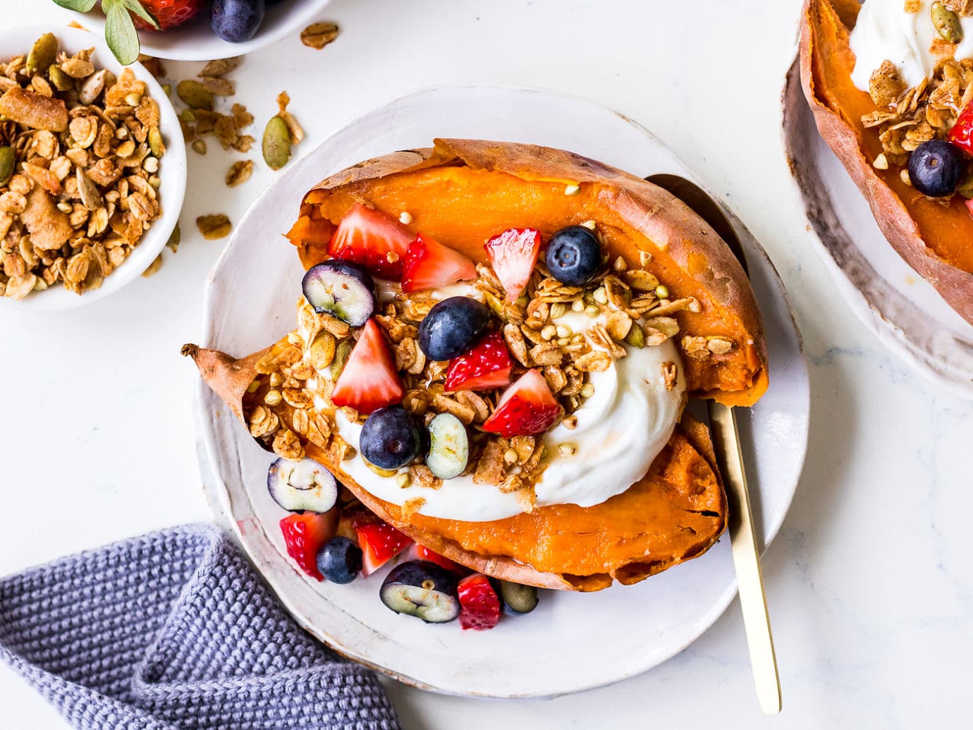 Small white plate with sweet potato topped with yoghurt, berries and granola