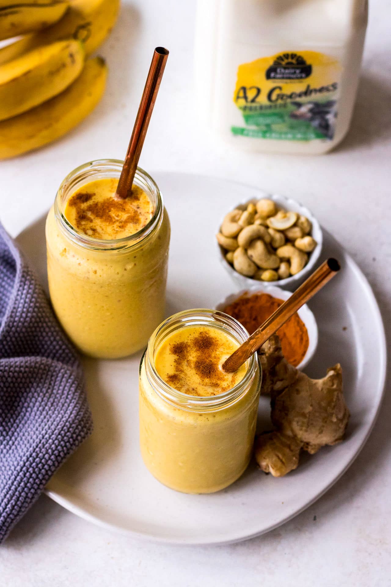 Golden milk smoothie in glass jars with copper straws, Dairy Farmers milk in the background
