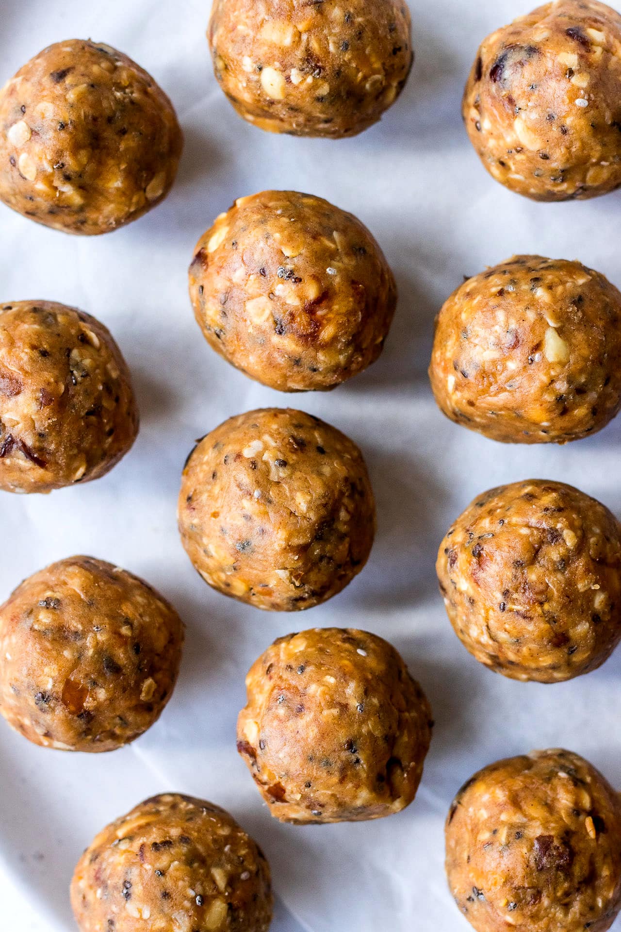 Close up of peanut butter energy bites with oats, chia seeds and dates, with a white background