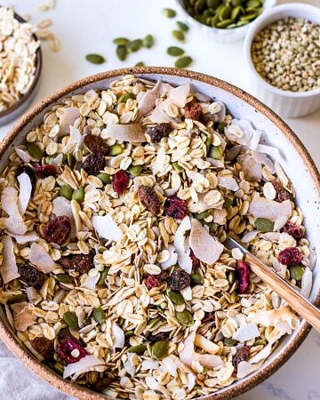 Large ceramic bowl filled with oat muesli with coconut flakes, pumpkin seeds and dried fruit