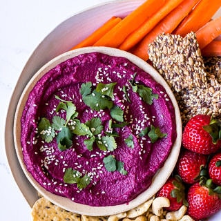 Dip platter with beet dip, carrot sticks, cashews, strawberries and seeded crackers
