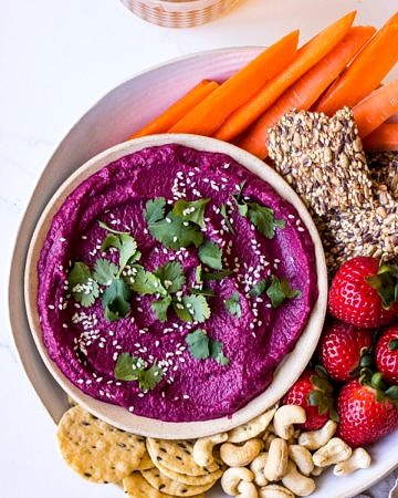 Dip platter with beet dip, carrot sticks, cashews, strawberries and seeded crackers