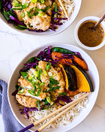 Irregular white bowls with rice, pumpkin, cabbage, chicken and miso dressing with herbs