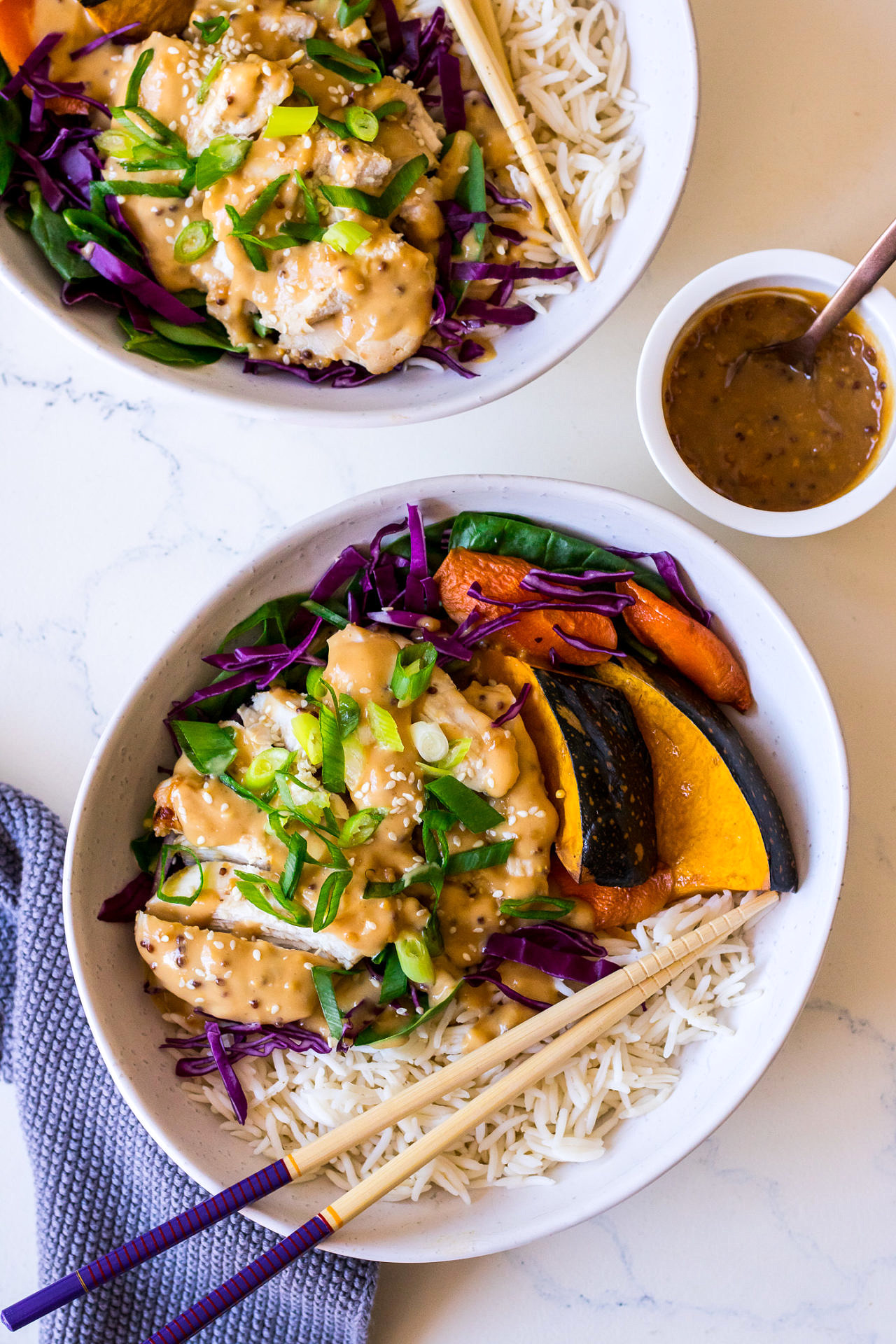 Irregular white bowls with rice, pumpkin, cabbage, chicken and miso dressing with herbs