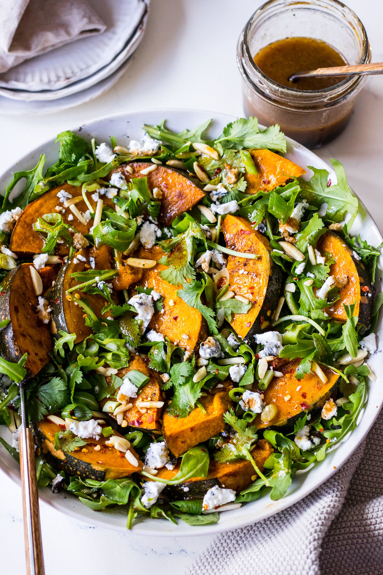 Roasted pumpkin, goats cheese and rocket salad in shallow ceramic bowl with balsamic dressing