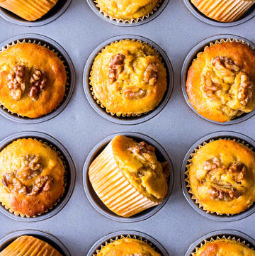 Pumpkin banana muffins topped with walnuts arranged in a muffin tin