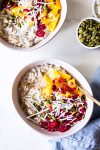 Two ceramic bowls with overnight oats, mango, coconut and raspberries