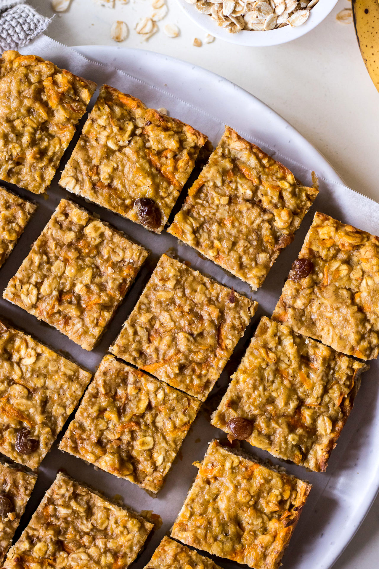 Square oatmeal bars with carrot and sultanas on a round ceramic plate