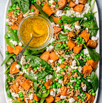 Salad of baby spinach, sweet potato and peas topped with feta, seeds and mustard dressing