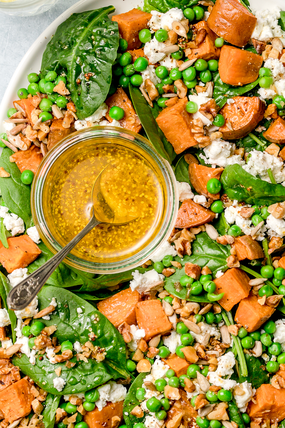 oval plate with sweet potato and baby spinach salad with mustard dressing