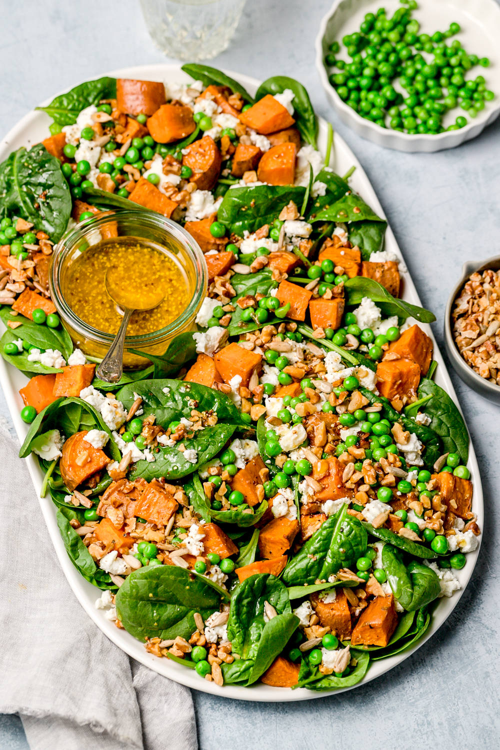 top view of baby spinach, sweet potato, pea and feta salad, mustard dressing