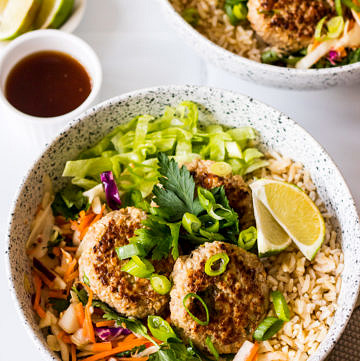 Lemongrass and ginger pork patties in a ceramic bowl with brown rice and salad