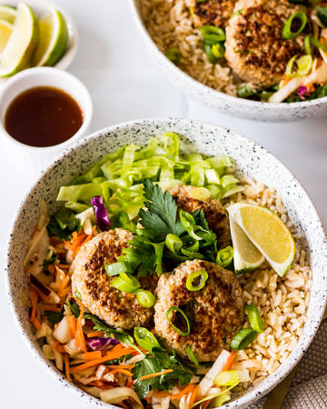 Lemongrass and ginger pork patties in a ceramic bowl with brown rice and salad