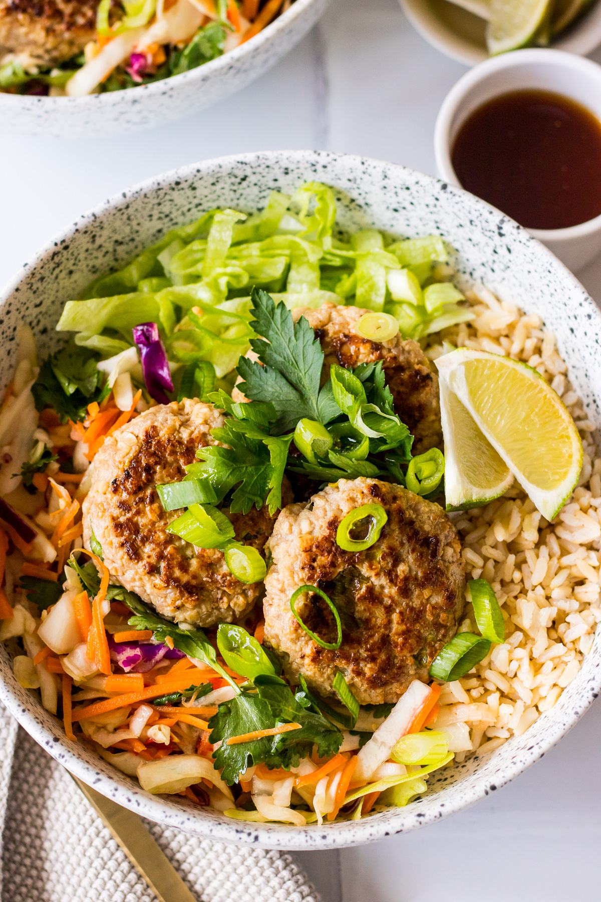 Lemongrass and ginger pork patties with spring onion, fresh salad, brown rice and soy dressing