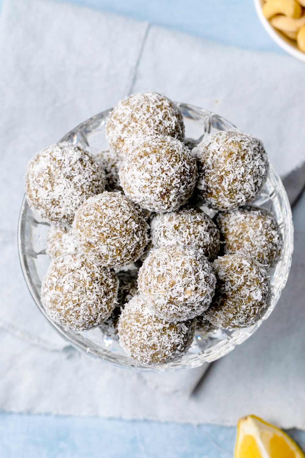 Top view of a small glass bowl filled with lemon cashew energy balls rolled in desiccated coconut