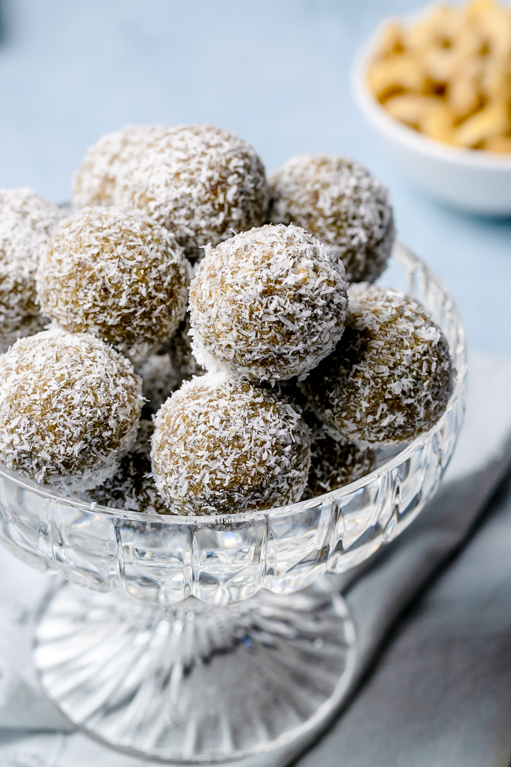 Medjool date and cashew energy balls rolled in desiccated coconut, in a glass bowl