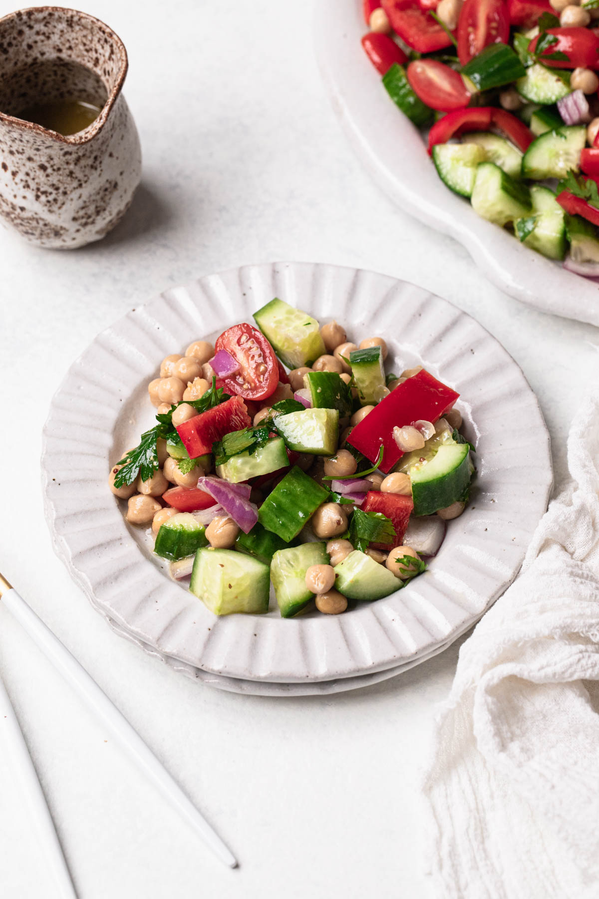 No Lettuce Chopped Salad of cucumber, cherry tomato, capsicum, red onion and chickpeas on a small white ridged plate